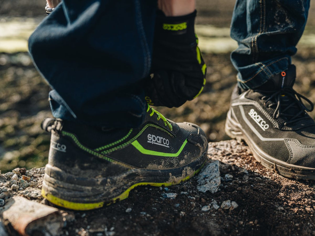 Sparco werkschoenen met modder op puin buiten